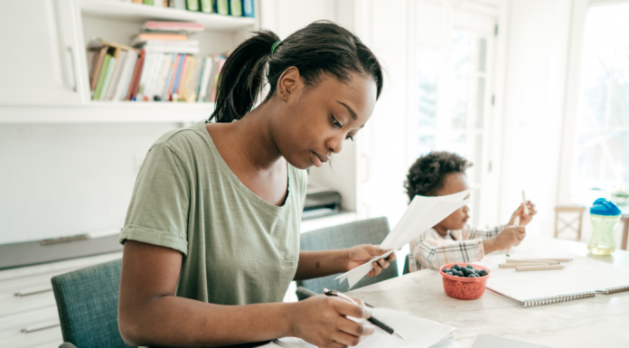 A mom working with her child sitting next to her.