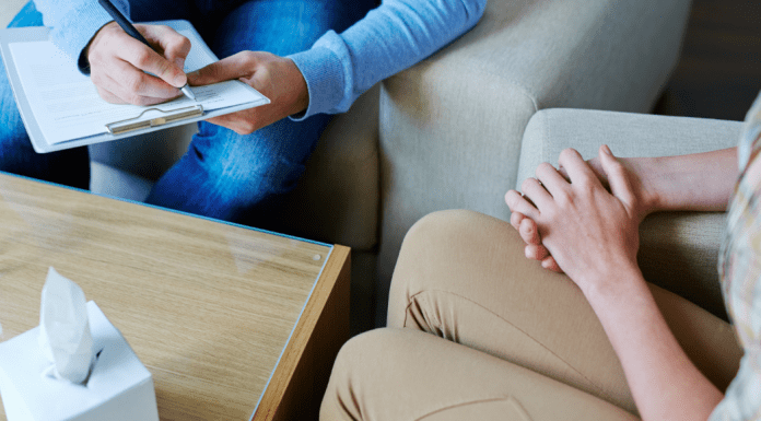 A woman sitting with her hands crossed with a therapist.