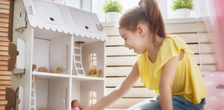 A girl playing with a dollhouse.