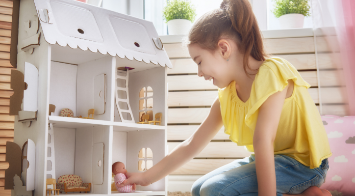 A girl playing with a dollhouse.