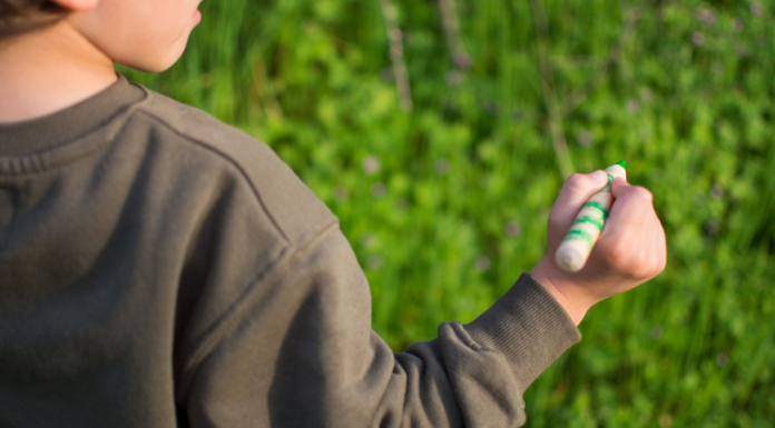 A boy holding a green crayon.