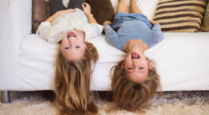 Sisters hanging upside down on the couch.