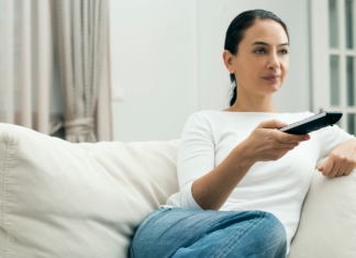 A woman holding a TV remote while sitting on the couch.