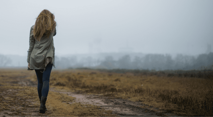 A woman walking on a dirt path.