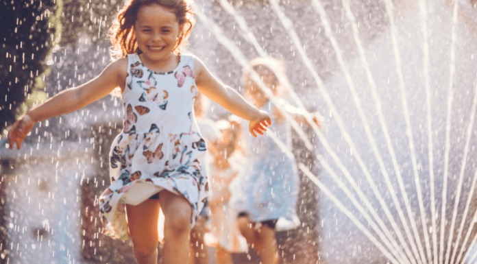 A girl running through a sprinkler.