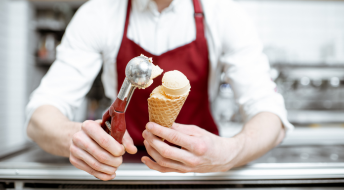 A man serving ice cream at an ice cream shop.