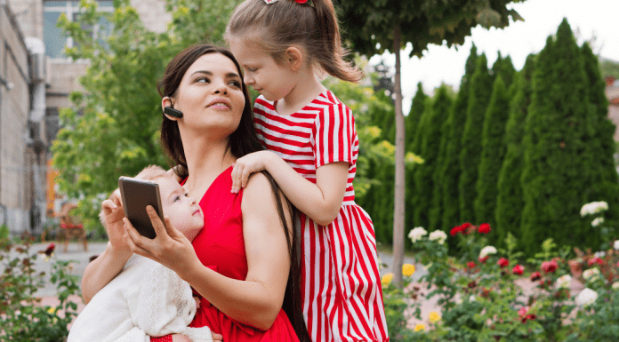 A woman working while holding her children.