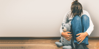 A woman holding a teddy bear after a miscarriage.