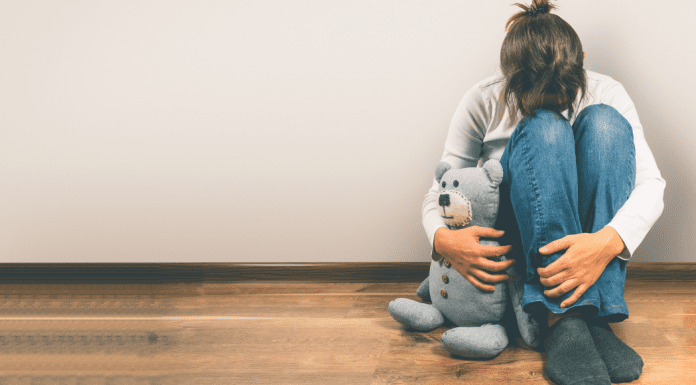 A woman holding a teddy bear after a miscarriage.