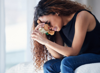 Ten Years After My Second Miscarriage, I Still Wonder A woman crying holding a stuffed animal.