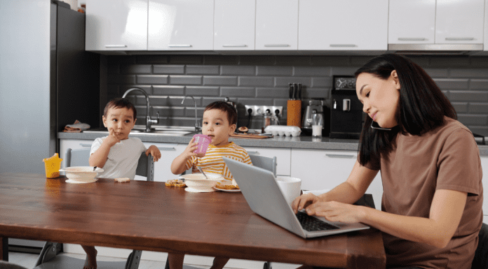 A mom working while her kids eat breakfast during the summer.
