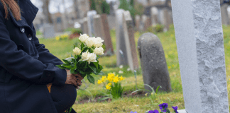 A woman putting flowers on a gravestone.