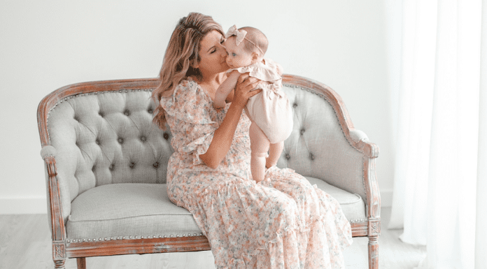 A mom holding a baby on a couch during a photography session.