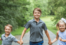 Three siblings holding hands.