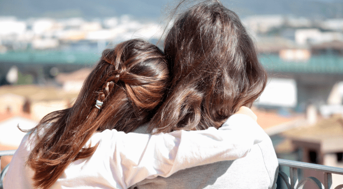 A daughter with her arm around her mother.