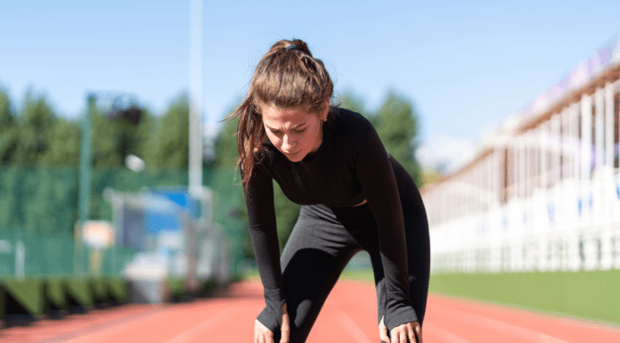 A woman catching her breath after running on a track.
