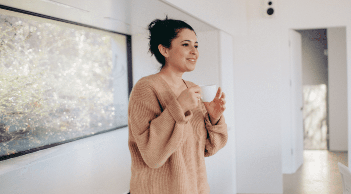 A woman smiling while drinking coffee.
