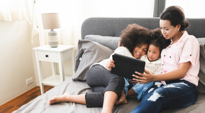 A mom looking at a tablet with her children.