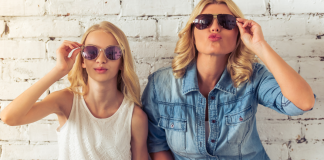 A mom and teen wearing sunglasses inside.