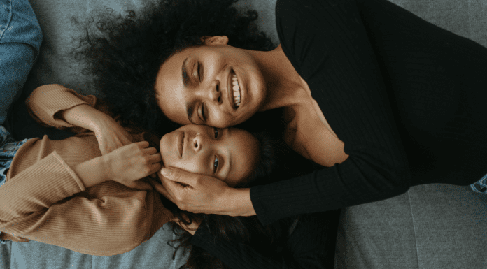 A mother and daughter laying next to each other head to head.