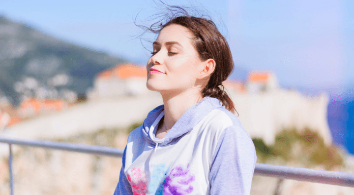 A woman taking a deep breath outside.