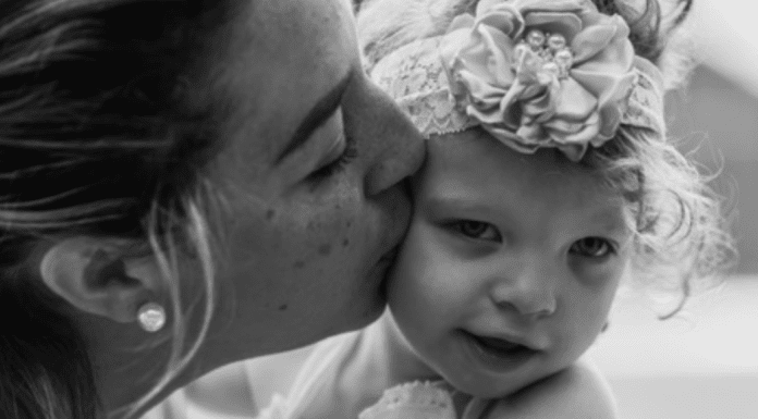 A mother kissing her daughter.
