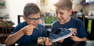Two boys pouring syrup into a shoe.