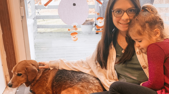 A woman holding her daughter and dog.