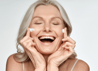 An older woman putting cream on her face.