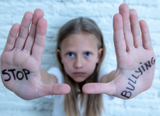 A girl holding up her hands with "Stop Bullying" written on them.