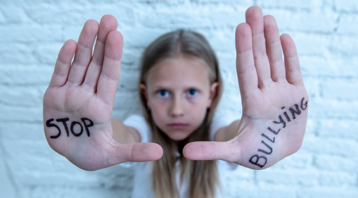 A girl holding up her hands with "Stop Bullying" written on them.