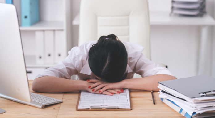 A woman with her head down on her desk.