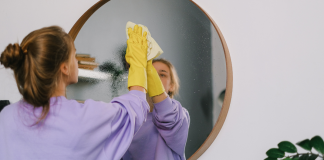A woman cleaning a mirror.
