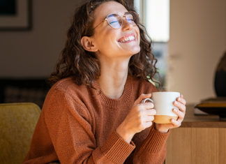 A happy woman smiling and holding a cup of coffee.