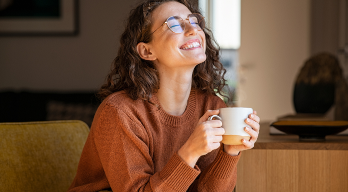 A happy woman smiling and holding a cup of coffee.