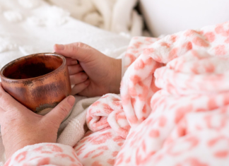 A woman holding a cup of coffee in bed.