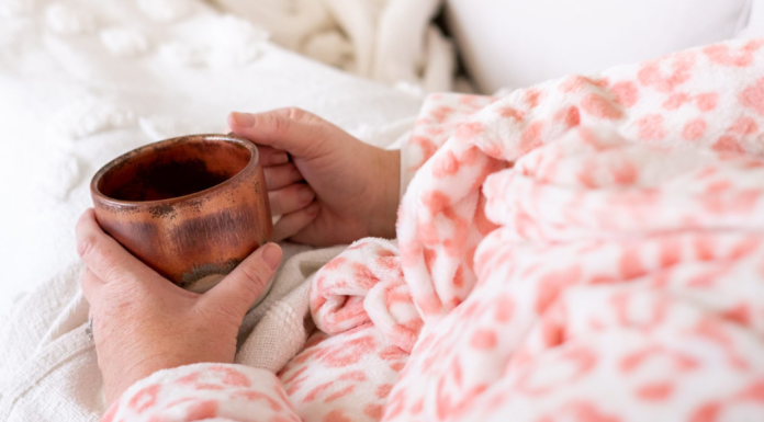 A woman holding a cup of coffee in bed.