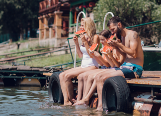 A family sitting on a dock eating watermelon.