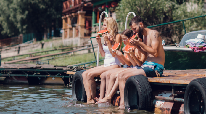 A family sitting on a dock eating watermelon.