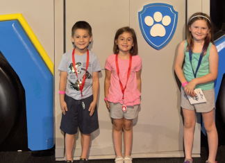 Kids standing in front of a Paw Patrol car.