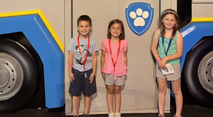 Kids standing in front of a Paw Patrol car.