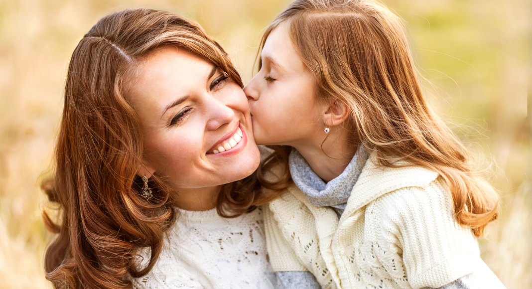 A daughter kissing her mother on the cheek.