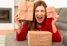 A stressed woman holding holiday gifts.