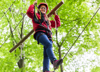 a girl climbing on a ropes course in the trees.