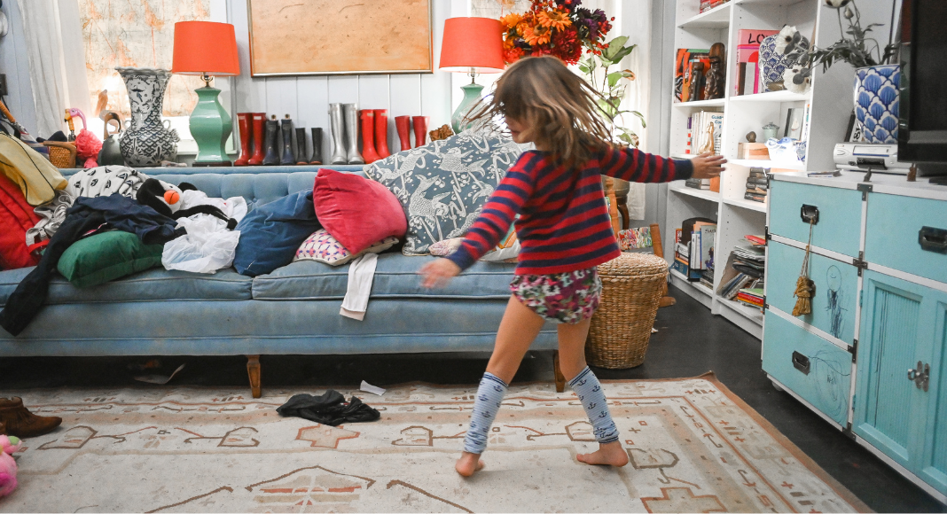 A child dancing in a chaotic living room.