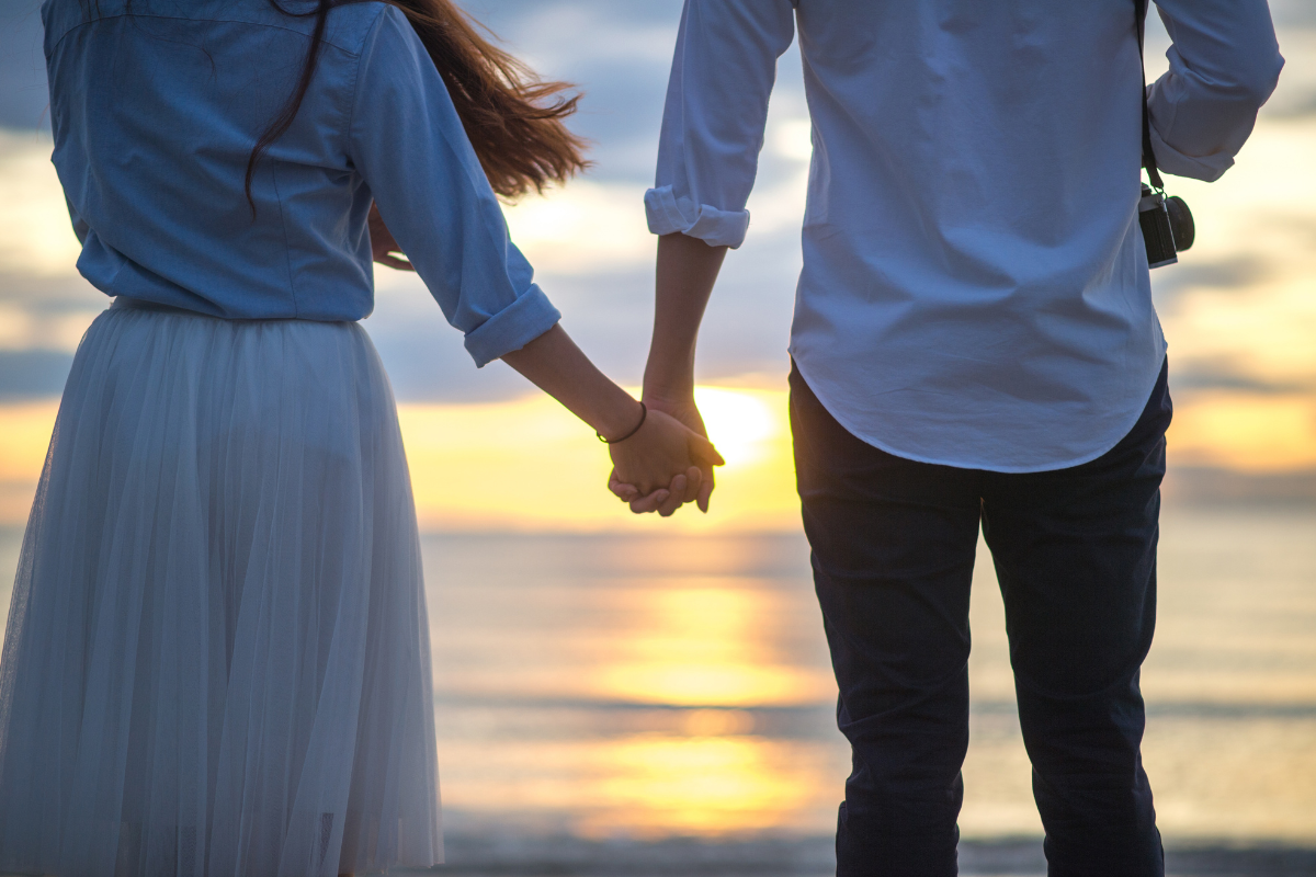 Couple holding hands by the ocean, relationships- Fairfield County Mom 