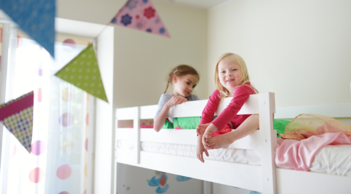 Sisters sitting in a top bunk bed.