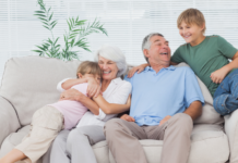 Grandparents snuggling grandchildren on a couch.