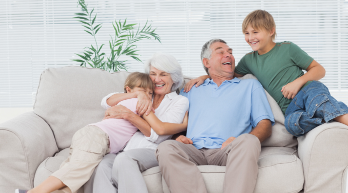 Grandparents snuggling grandchildren on a couch.