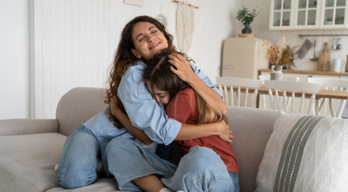 A mom hugging her teen daughter.